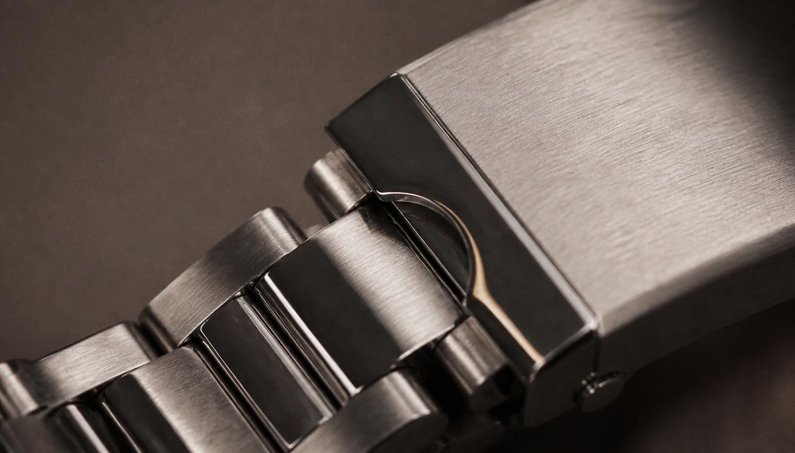Macro photograph of a brushed and polished steel watch bracelet and clasp